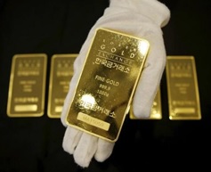 An employee poses for photographs with a one kilogram gold bar at the Korea Gold Exchange in Seoul, South Korea, July 31, 2015. REUTERS/Kim Hong-Ji/Files